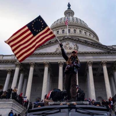 En man viftar med USA:s flagga utanför Capitolium.