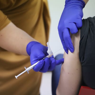 En persons arm blir stucken med en spruta med vaccin. 
