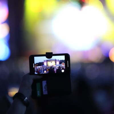 En mobil hålls upp i ett publikhav och filmar ett framträdande under Pori Jazz 2019.