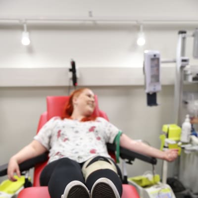 nuori nainen makaa verenluovutuksessa punaisella tuolilla