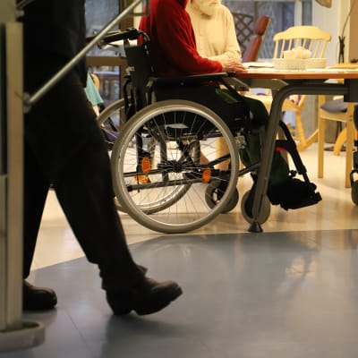 Två rullstolsburna personer sitter vid ett matbord.