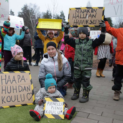 Äiti ja lapset puolustavat kyltein koulua mielenosoituksessa