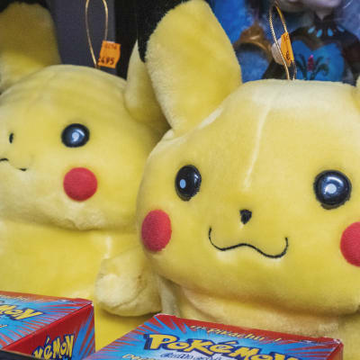 Två gula mjukisfigurer, framför dem askar med texten "Pokémon"