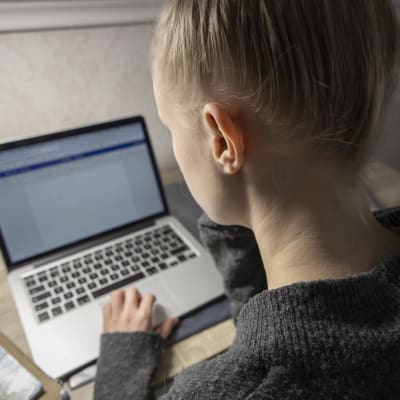 Ung person skriver studerar vid bärbar dator. 