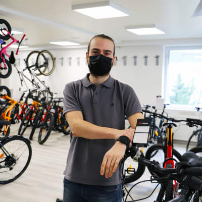 Aleksi Sanaksenaho står bredvid cyklar i en cykelaffär.