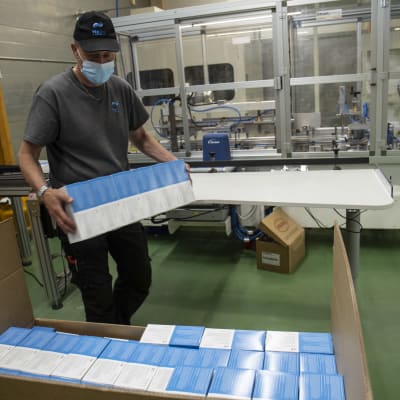 En anställd packar förpackningar med munskydd.