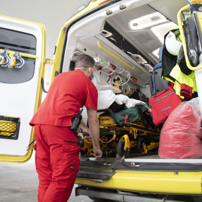 Förstavårdare lastar in en person i en ambulans.