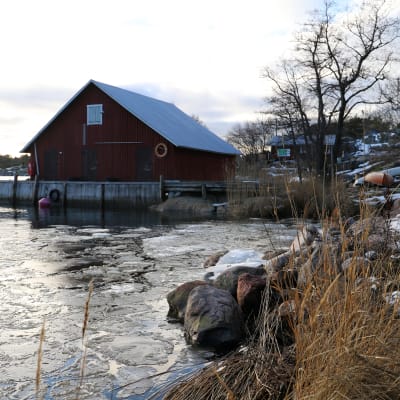 Ett rött båthus i en isig vik. 