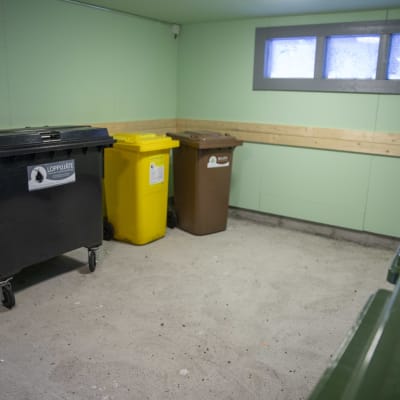 Behållare för olika material som ska återvinnas, finns i ett rum.