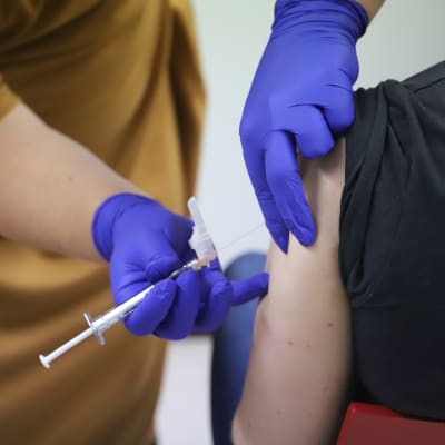En persons arm blir stucken med en spruta med vaccin. 