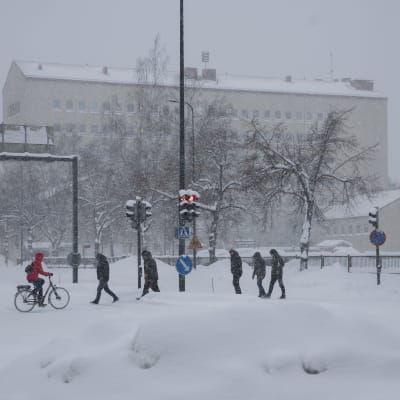 Lumipyry Kouvolan keskusta-alueella ja liikennevaloissa käveleviä henkilöitä.