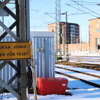 En skylt vid en järnväg där det såt Se upp för tåget. 