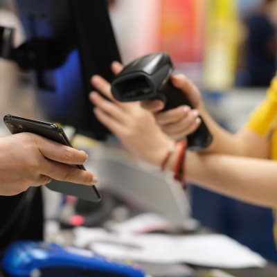 Person betalar med telefonen i en butikskassa.