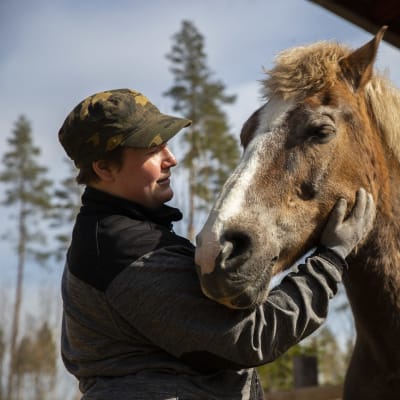 Janika Kivikko silittämässä Pampam -hevostaan Kouvolan Elimäellä.