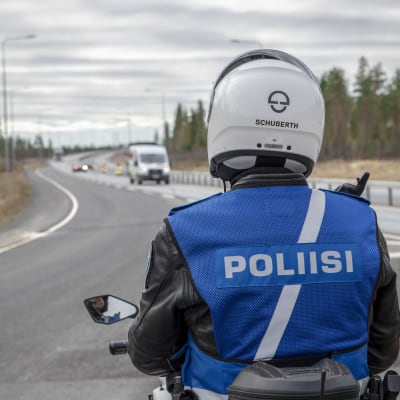 En motorcykelpolis tittar ut över trafiken på en stor väg.