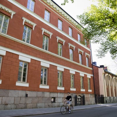 Fasaden på Katedralskolan i Åbo, en person cyklar förbi. 
