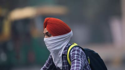 En man som rör sig i trafiken i New Delhi skyddar sig mot luftföroreningar 4.11.2019
