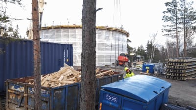 Ett vattentorn intäckt i vitt plast. I framgrunden ser man en man som jobbar med att bygga tornet. 