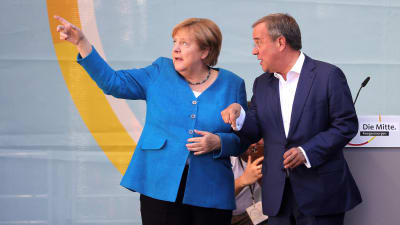 Angela Merkel osoittaa sormellaan itsestään oikealle, Armin Laschet katsoo sormen suuntaan