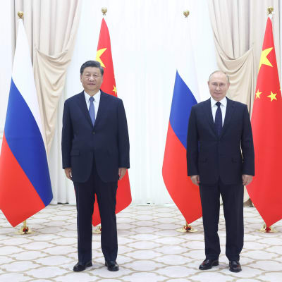 Kokokuvassa Vladimir Putin ja Xi Jinping seisovat vierekkäin. Taustalla Venäjän ja Kiinan lippuja.