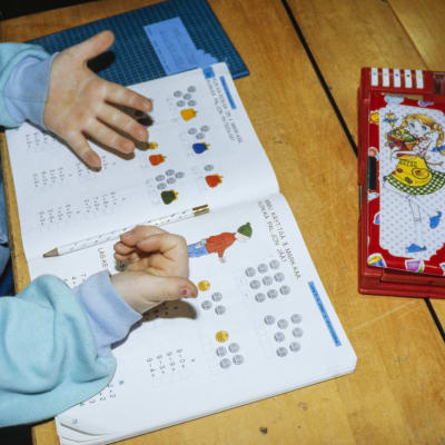 Lapsi laskee matematiikan tehtävää sormillaan.