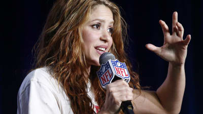 Sångaren Shakira uppträder. Hon håller i en mikrofon med NFL:s logo.