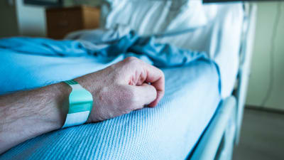 Närbild på en mans arm i en sjukhussäng.