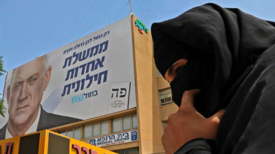 En beduinkvinna passerar en av Gantz' valaffischer i Beersheva, i södra Israel. 