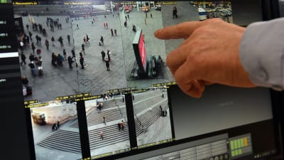 En tysk polis pekar på en skärm med övervakningsbild från torget i Köln.
