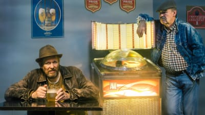Tvä män i en bar med en jukebox mellan sig