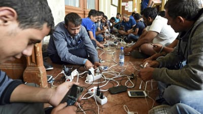 Flyktingar får ladda sina telefoner på järnvägsstationen i Budapest.