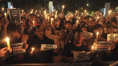 Personer med ljus sörjer offren i tumultet i Indonesien där 125 personer dog.
