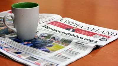 En kaffemugg placerad på en dagstidning.