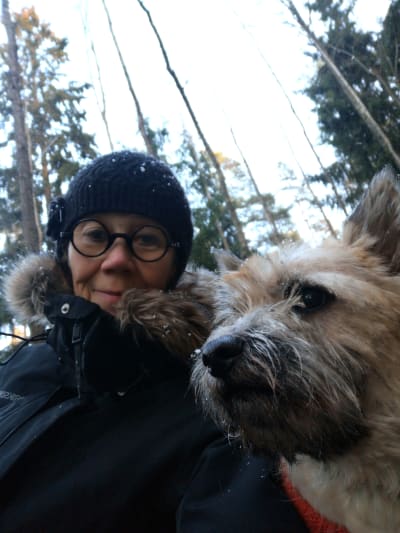 Marja Saarenheimo koiransa Kaapon kanssa lähikuvassa, joka on otettu talvisessa metsässä läheltä kasvoja.