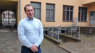 Mikael Erkas står ute på en innergård.