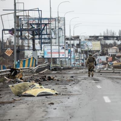 Ukrainalainen sotilas kävelee kadulla tuhojen keskellä.