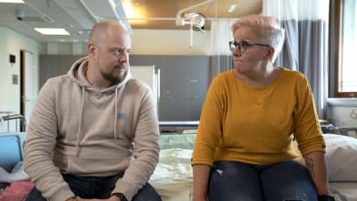 Nainen ja mies istuvat sairaalasängyn reunalla. 
