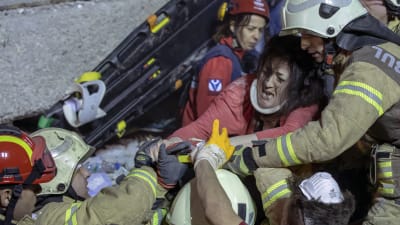 Räddningsmanskap bär ut en skadad kvinna från rasmassorna efter att ett flervåningshus rasade i Istanbul,.
