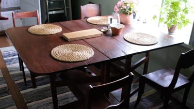 Ett mörkbrunt klaffbord med fyra stolar i en matsal. 