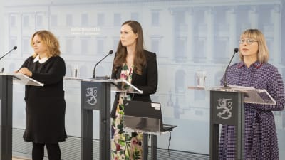Ministrarna Krista Kiuru, Sanna Marin och Aino-Kaisa Pekonen står framför varsitt podie och pratar på en presskonferens.