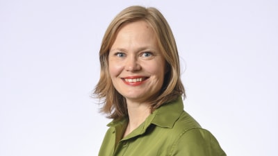 Porträtt bild av riksdagsledamot Hanna Kosonen. Hon är klädd i grön skjorta och är fotad mot vit bakgrund. 