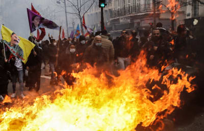 Domstranter på gatan i Paris, framför dem stora eldlågor.