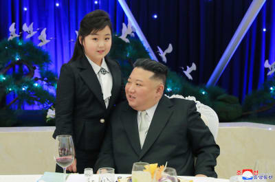 Nordkoreas ledare Kim Jong-Un sitter vid ett bord med dottern Kim Ju-Ae stående bredvid.