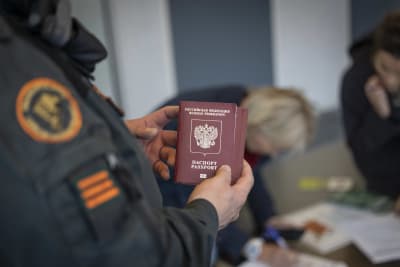 En gränskontrollant håller i ett ryskt pass.