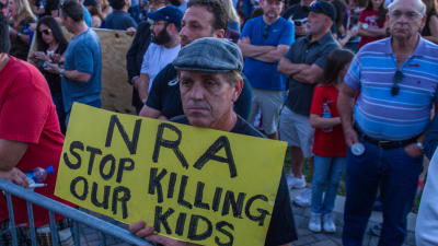 En man demonstrerar mot vapenlobbyn NRA (National Rifle Association) under minnesstunden för dödsoffren i Parkland, Florida på torsdag kväll. "NRA sluta döda våra barn" står det på plakatet.