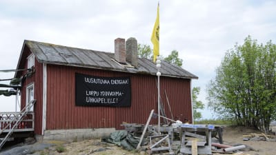 Röd sommarstuga som kärnkraftsaktivister fått överta, plakat på vägen