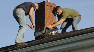 Två män reparerar en skorsten med jesustejp efter en jordbävning i Virginia i USA i augusti 2011.