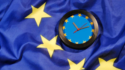 Bild föreställande en klocka med EU:s flagga i bakgrunden. 