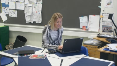 Jasmin Bilenberg sitter i ett tomt klassrum och undervisar eleverna med hjälp av dator. 