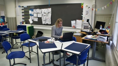 Jasmin Bilenberg sitter i ett tomt klassrum och håller distansundervisning med hjälp av en dator.